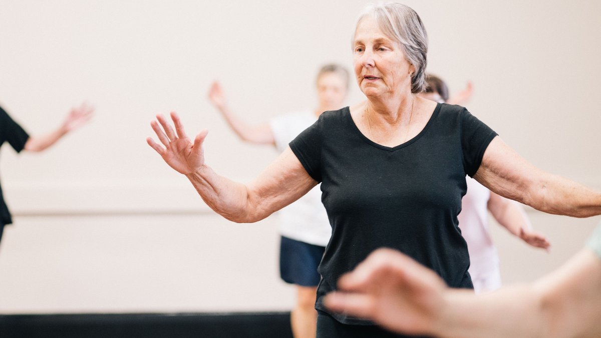 Elderly women enjoying a fitness group exercise session indoors.