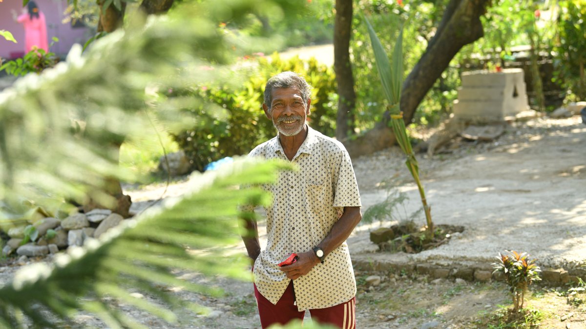 Happy senior man enjoying a bright sunny day in a lush garden landscape.