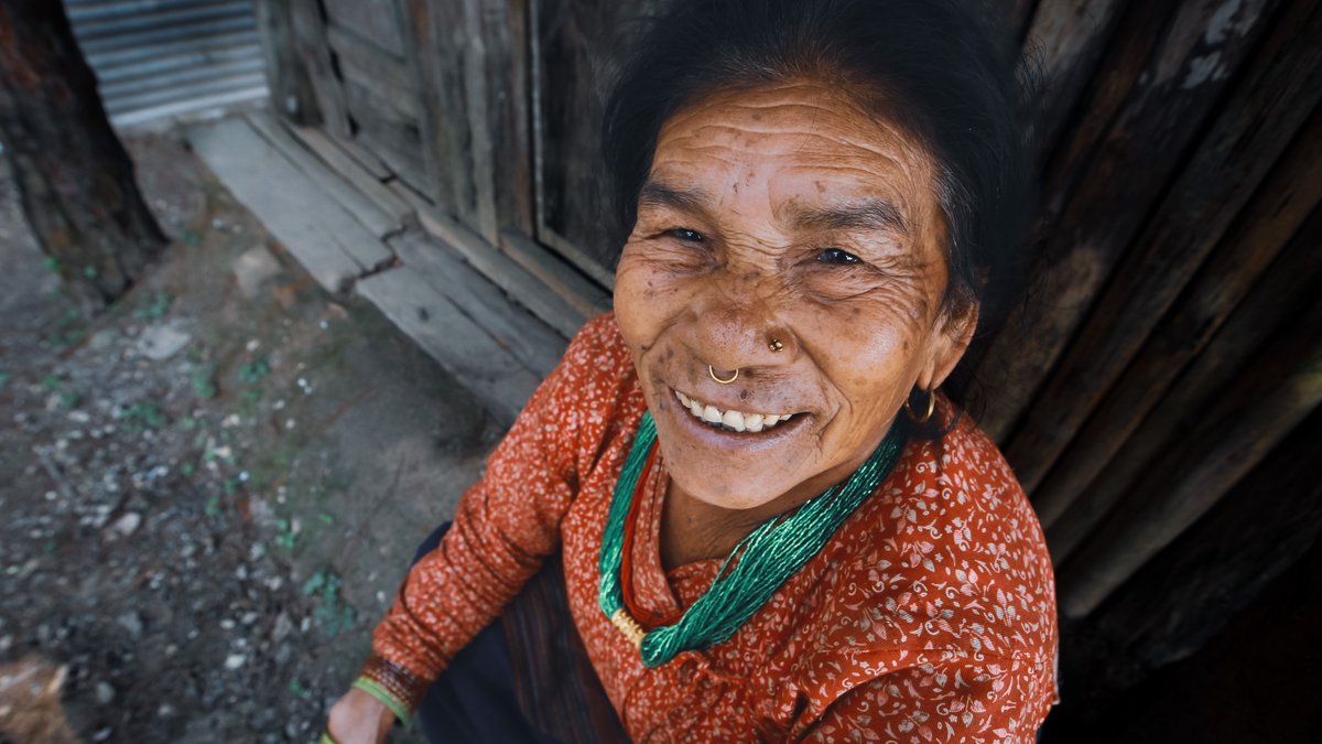 Elderly woman in traditional dress smiling warmly, showcasing cultural beauty and joy.