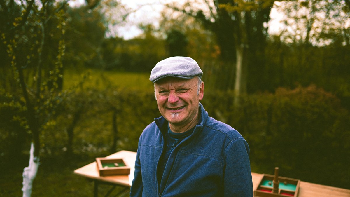 Smiling elderly man wearing a cap in a garden setting, epitomizing retirement joy.