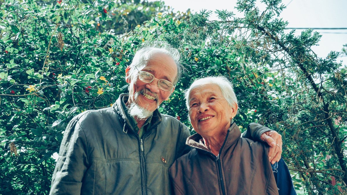 Senior couple enjoying a joyful moment together in a lush garden setting, exuding love and happiness.