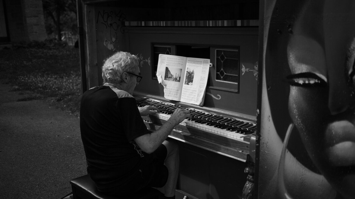 A senior man plays piano on a city street, creating urban harmony.