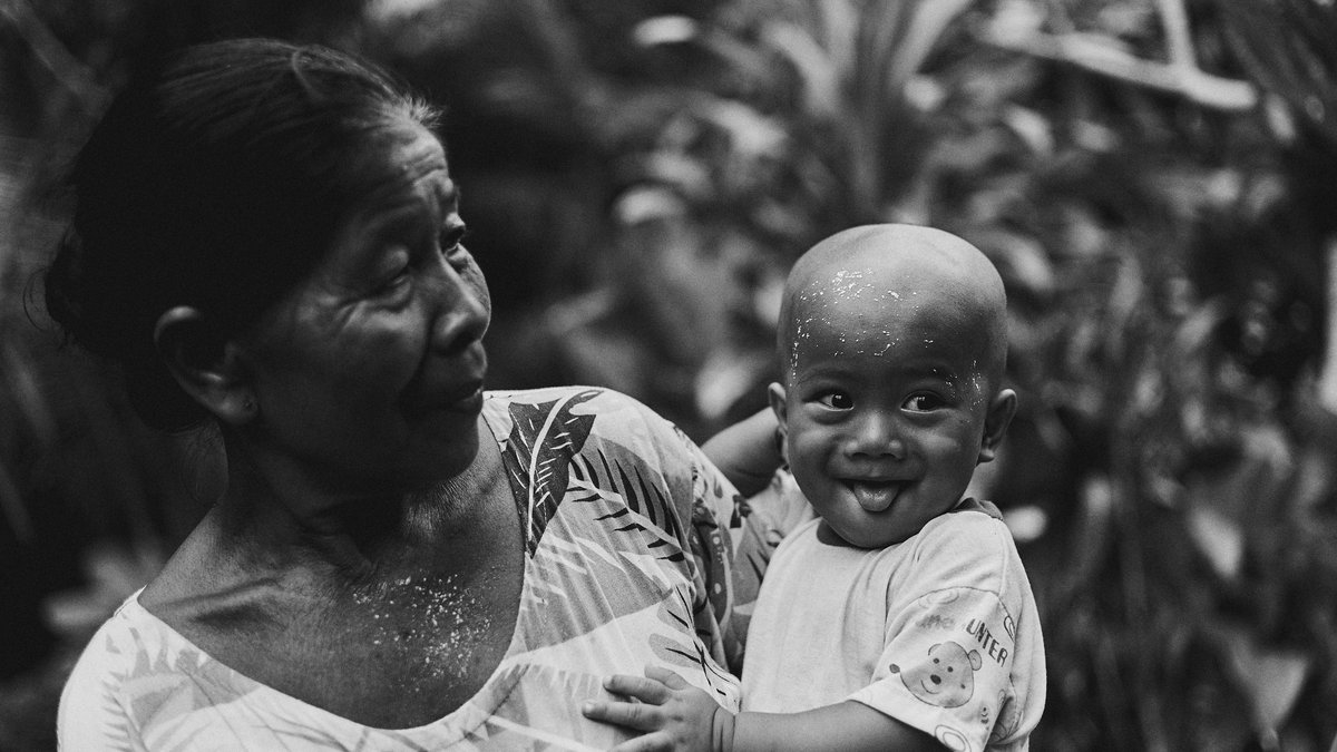 Joyful moment of a grandmother holding her playful grandchild among nature in black and white.