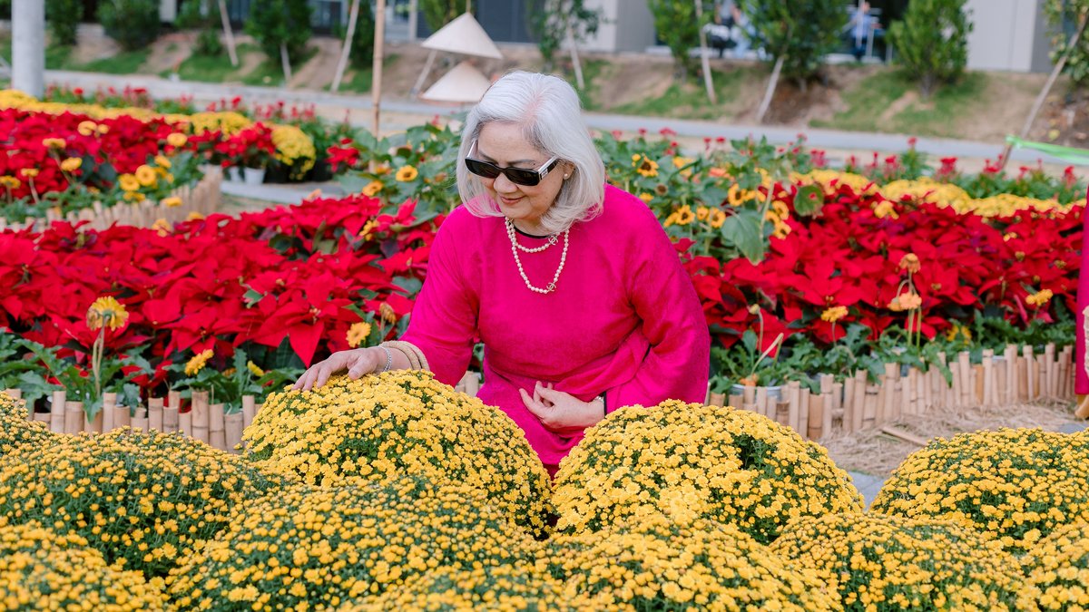 Senior woman in pink enjoys colorful flowers in a sunny garden.