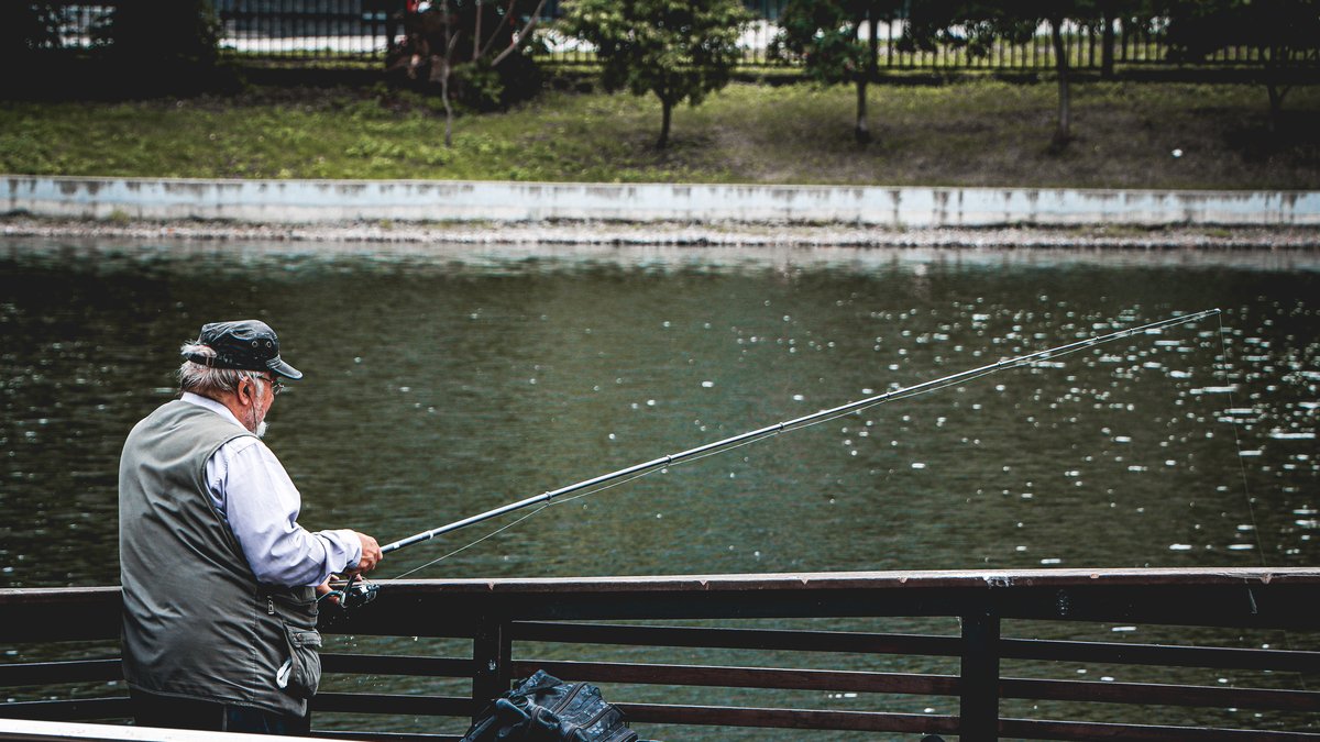 Senior man enjoying a peaceful day of fishing by the lake, surrounded by nature.