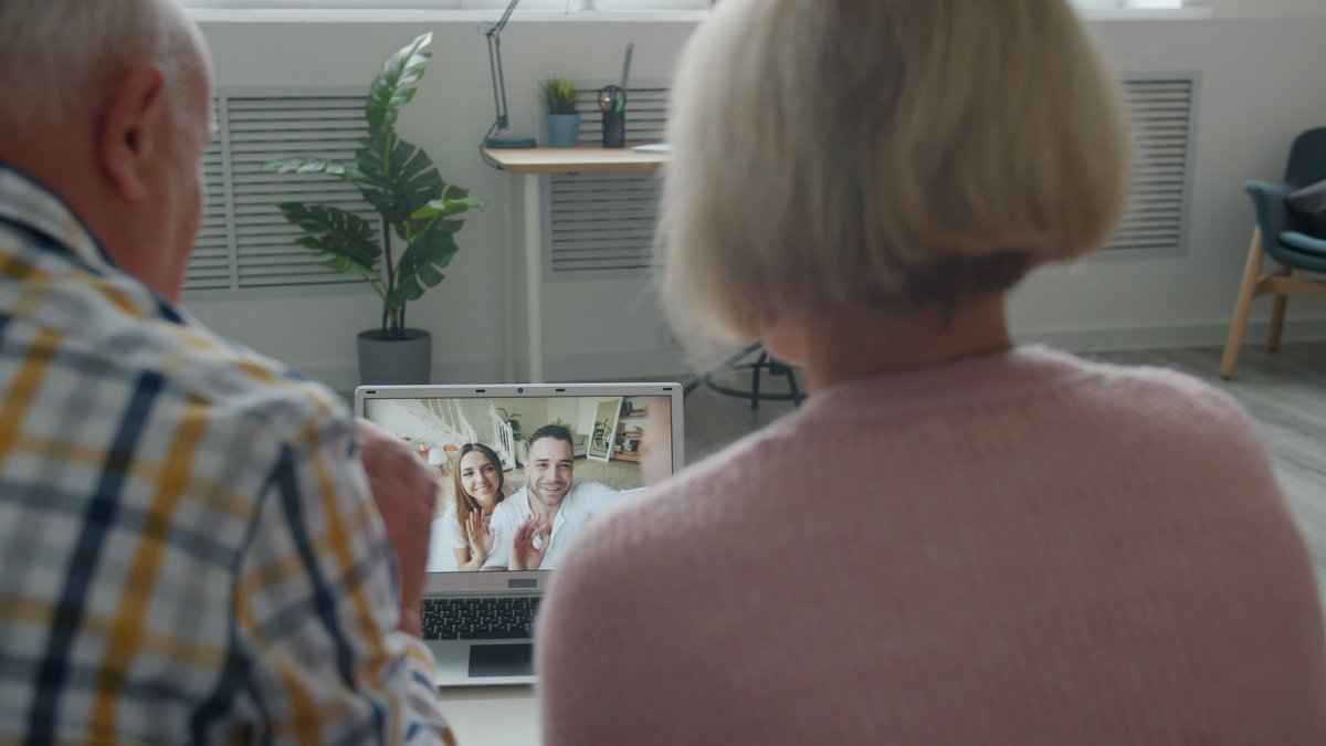 Elderly couple having a video call with family on a laptop at home.