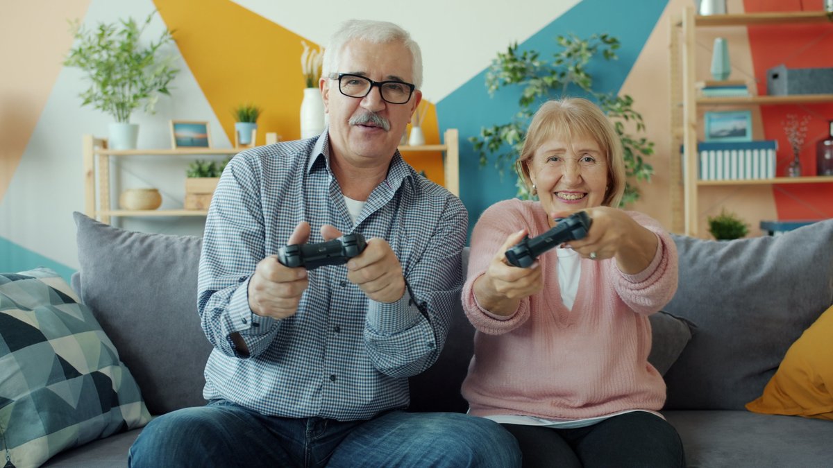 Cheerful senior couple playing video games together at home showcasing active lifestyle.