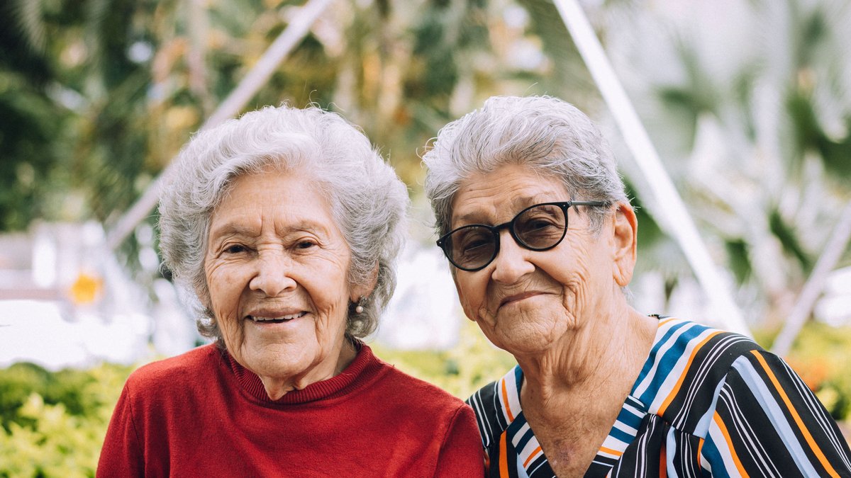 Two senior women enjoying a sunny day, smiling outdoors in Gigante, Colombia.