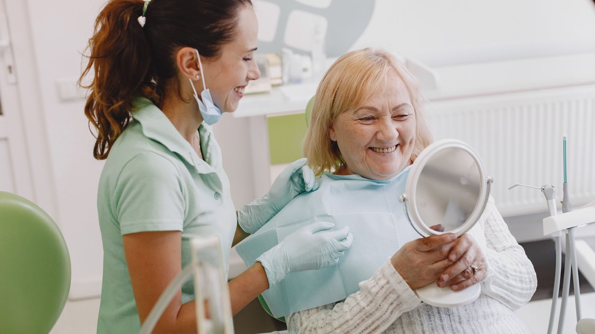 Senior patient at a dental check-up, smiling with the dentist in a modern clinic.
