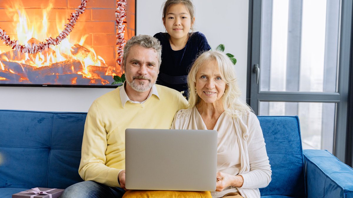 Three generations enjoying time together around a laptop during a cozy indoor gathering.