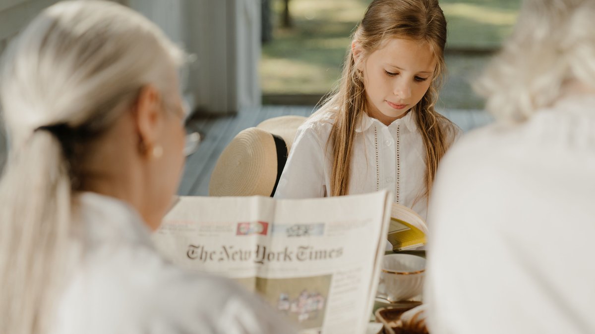 A serene scene of a grandmother and granddaughter reading together on a sunny porch.