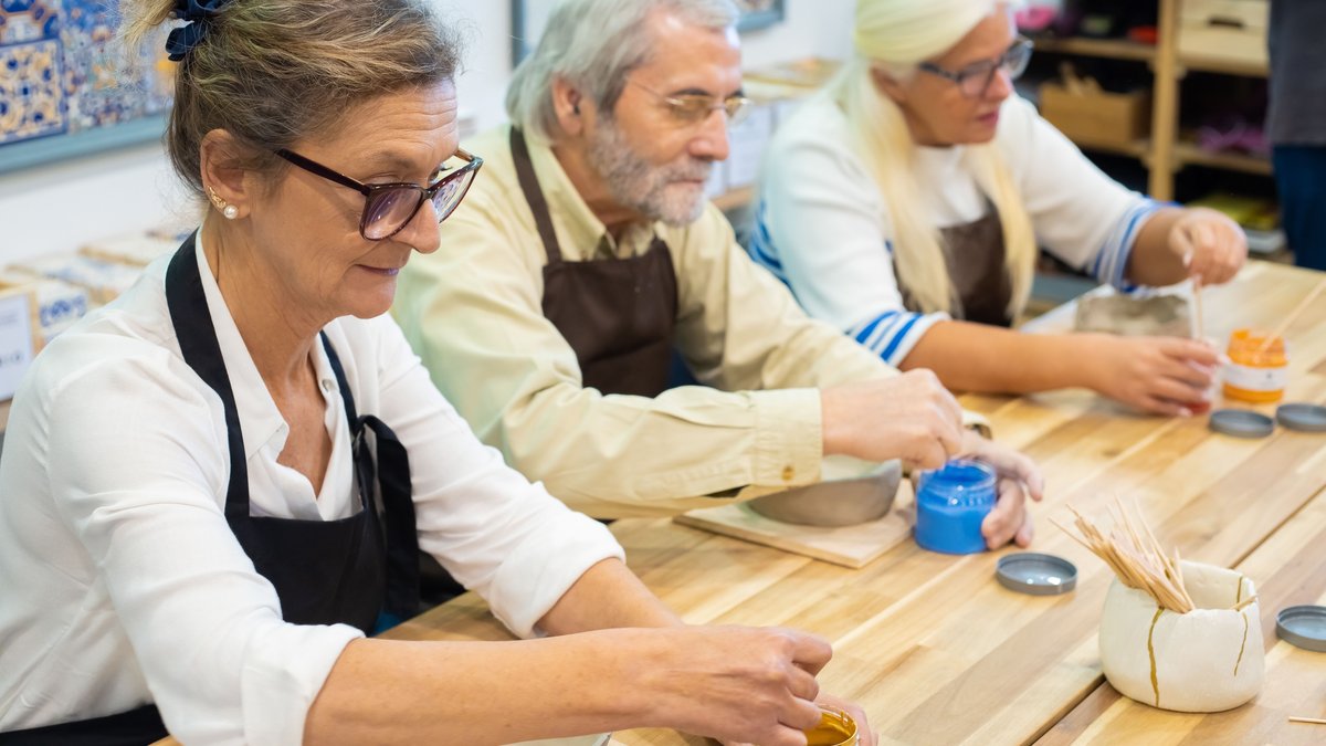 Senior adults enjoying a pottery painting workshop, showcasing creativity and craftsmanship.