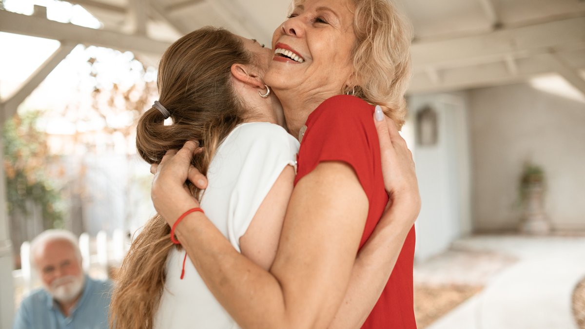 Heartwarming moment of two women sharing a joyful hug outdoors.