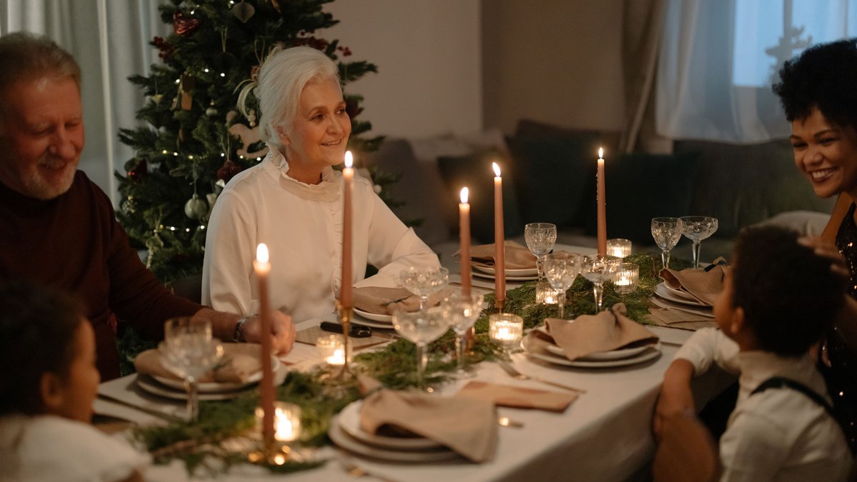 Family enjoying a festive Christmas dinner with smiles and holiday decorations.