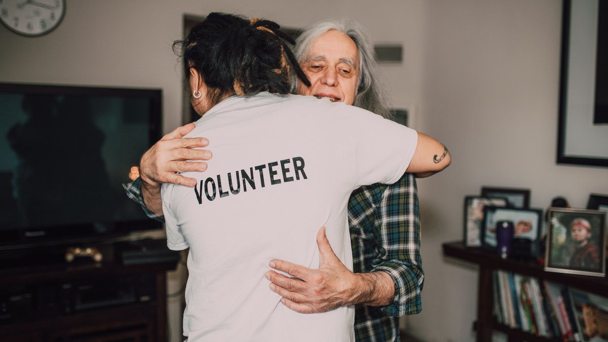 A volunteer embraces a senior woman in a heartfelt moment of support and love.