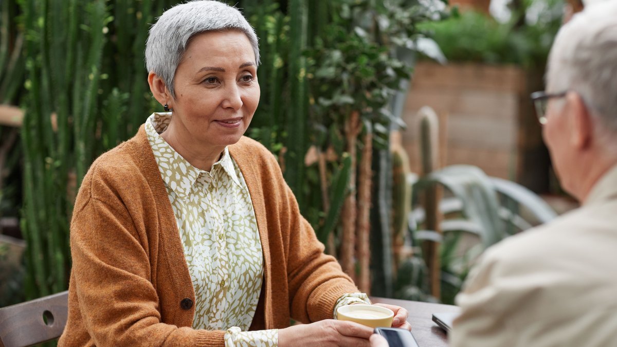 A senior couple enjoying coffee and conversation in a lush garden setting