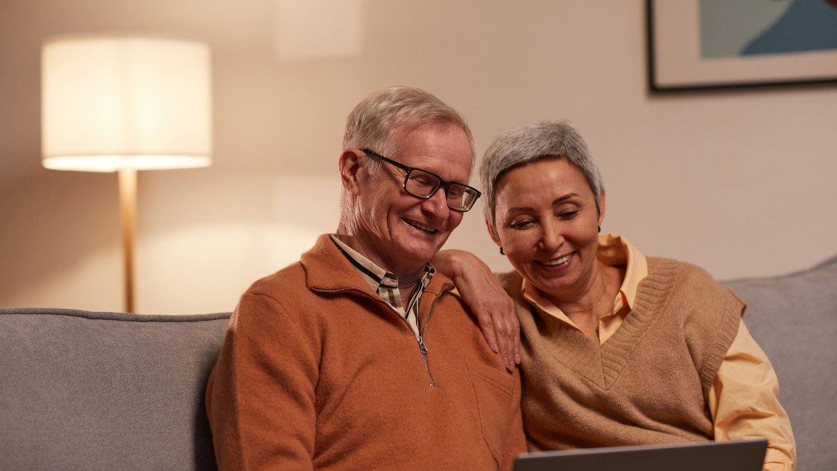 Senior couple enjoying time together on laptop indoors, smiling and relaxed.