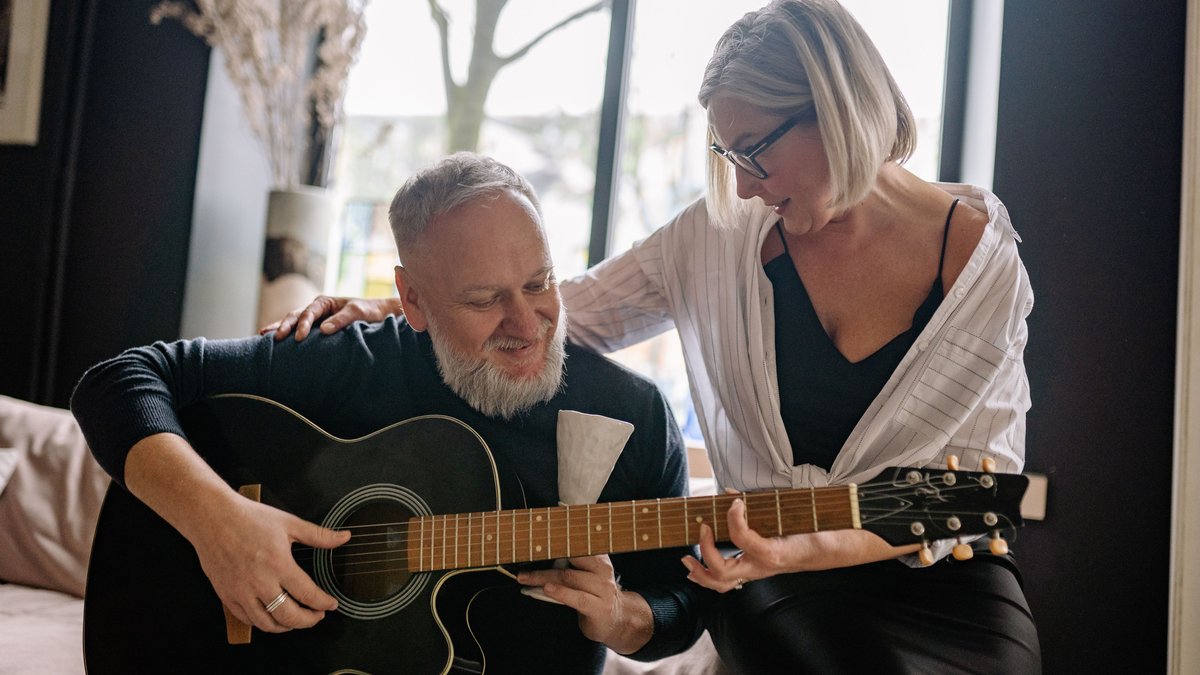 A joyful elderly couple spending quality time playing guitar and enjoying music together indoors.