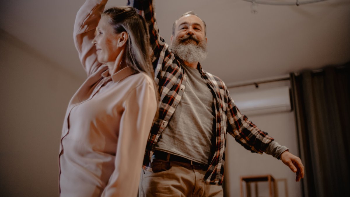 An elderly couple enjoying a dance together in their cozy living room, showcasing love and companionship.