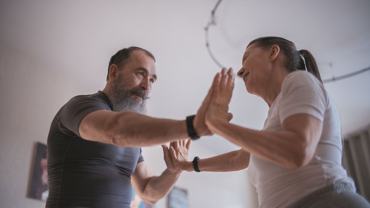 A joyous elderly couple dancing and connecting indoors, emphasizing love and friendship.
