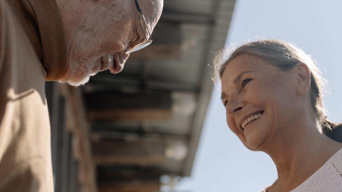 Happy senior couple sharing a smile in a cozy outdoor setting, capturing a moment of love and connection.