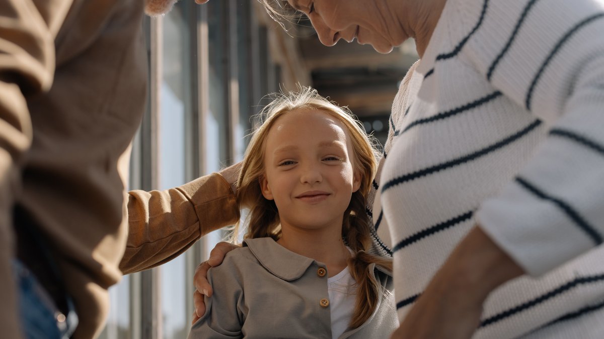 A joyful girl embraced by her loving grandparents, smiling and bonding together.