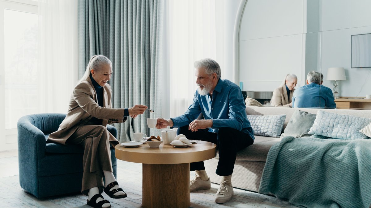 Elderly couple relaxing with coffee indoors, enjoying leisure time together.