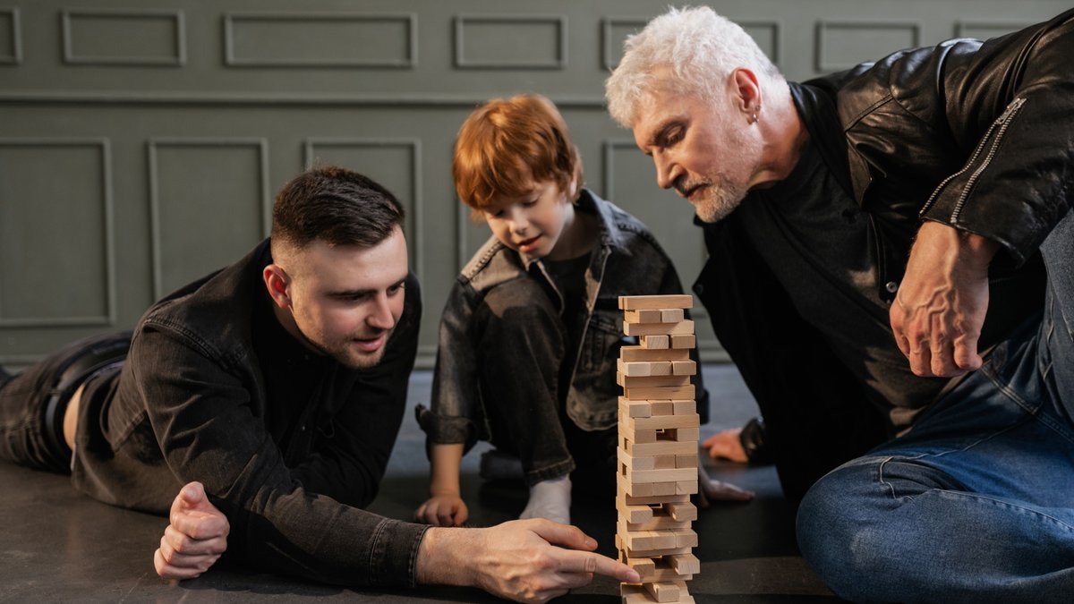 A joyful family scene with a grandparent, parent, and child enjoying a game of Jenga together.