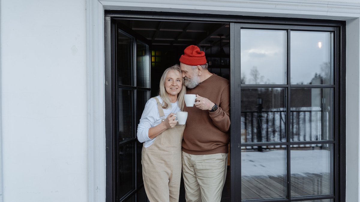 Happy senior couple enjoying coffee together outdoors, embracing lovingly.