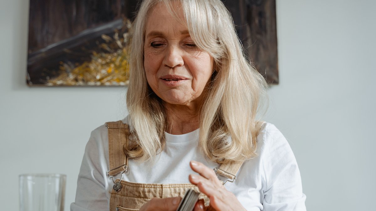 Cheerful senior woman playing cards at home, enjoying a relaxing moment.