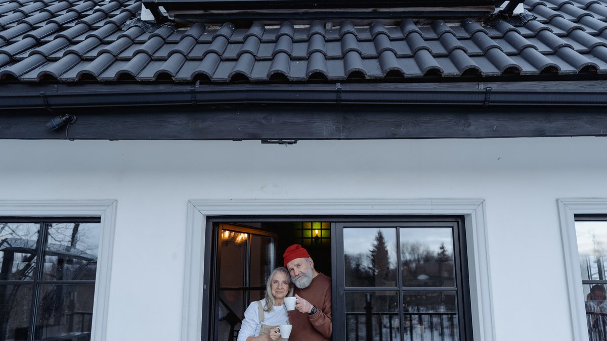An elderly couple enjoying coffee together indoors, showcasing love and happiness.