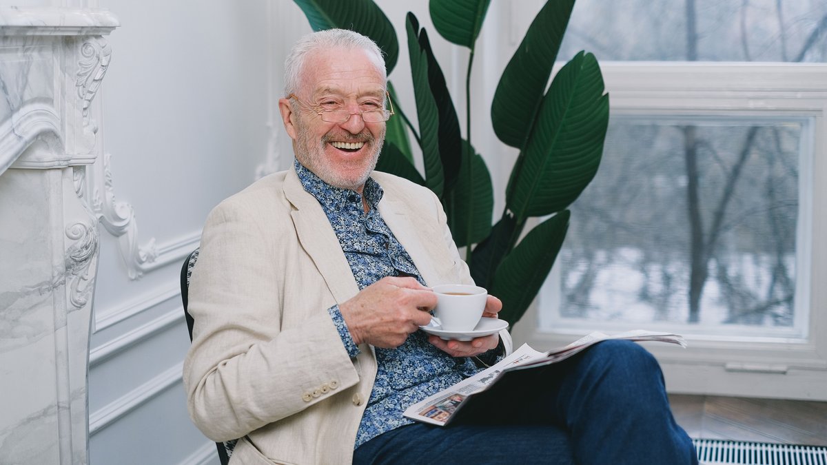 Cheerful senior man enjoying tea while relaxing indoors. Perfect depiction of leisure and contentment.