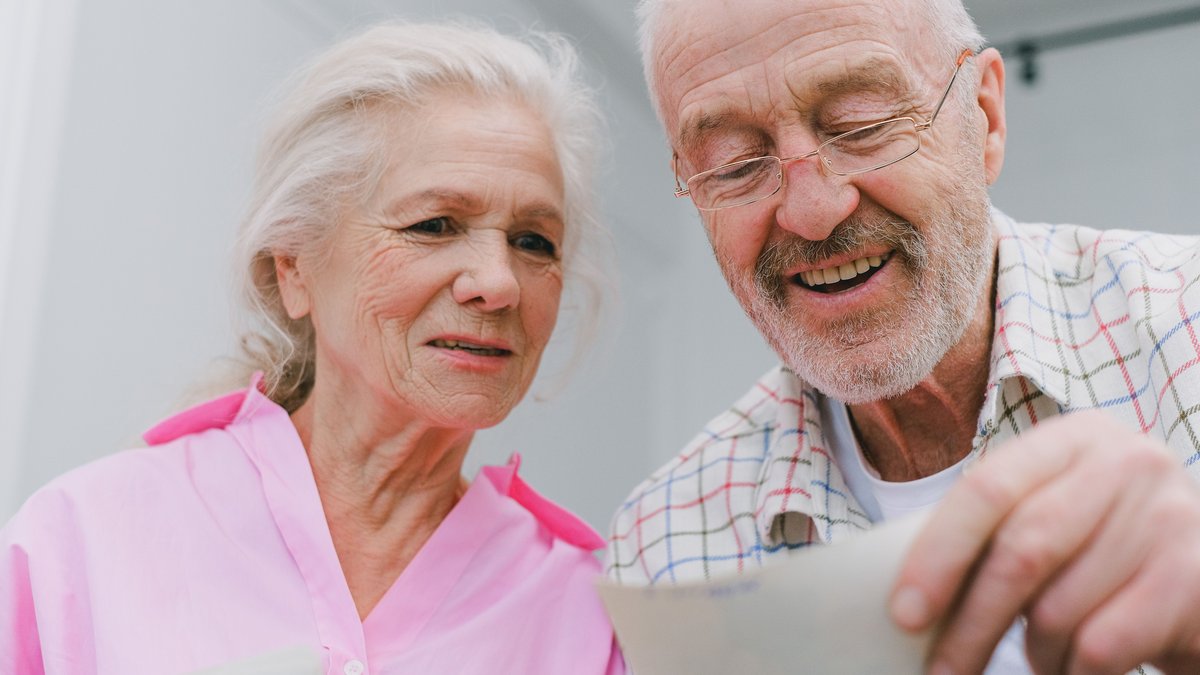 Happy senior couple enjoying old photographs and sharing memories together.