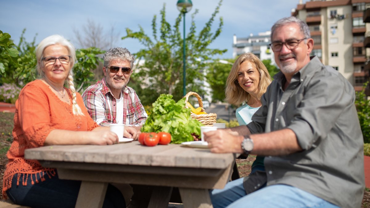 Happy group of seniors enjoying a picnic outdoors with fresh vegetables.
