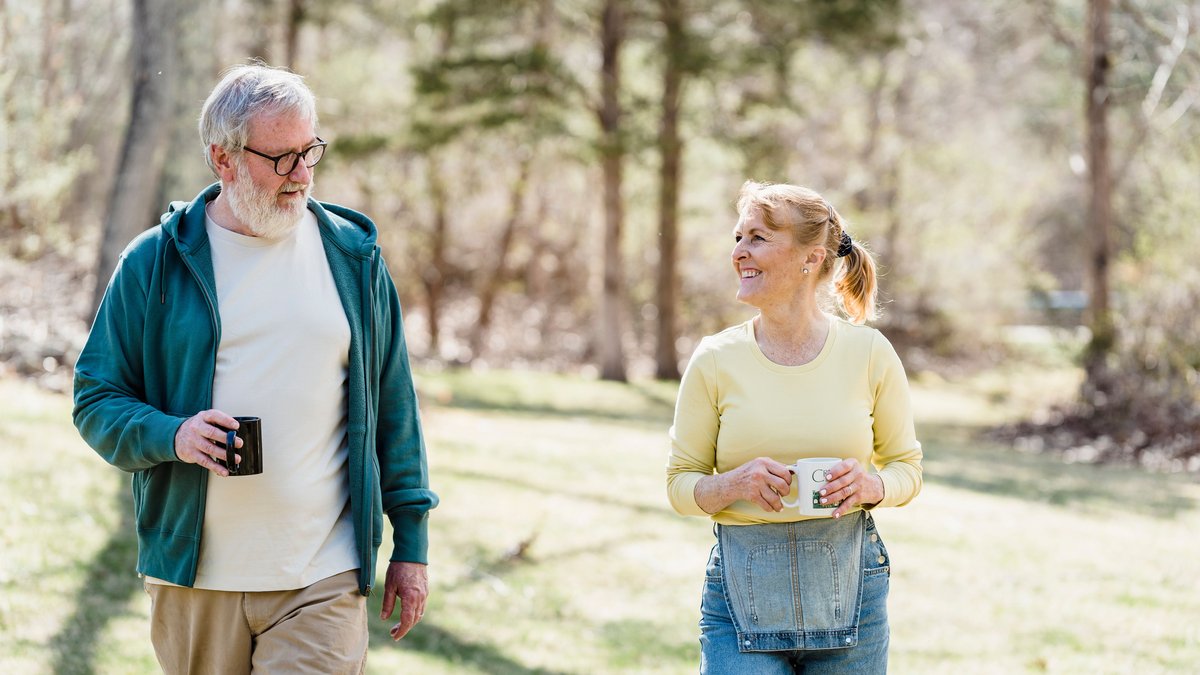 Happy elderly couple walking outdoors, sharing a joyful conversation with warm smiles.