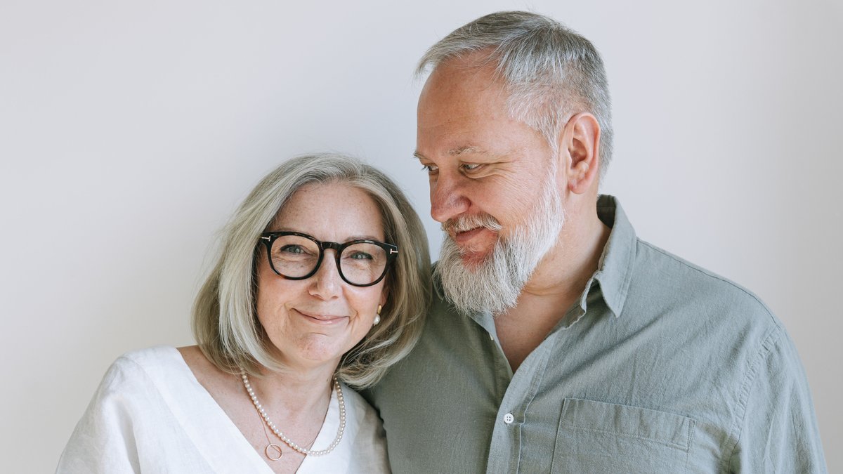 Happy senior couple smiling together indoors, showing warmth and love.