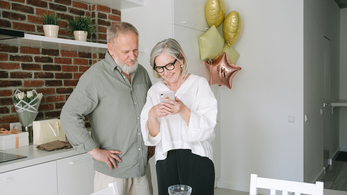 A cheerful senior couple enjoying a video call together in a cozy kitchen.