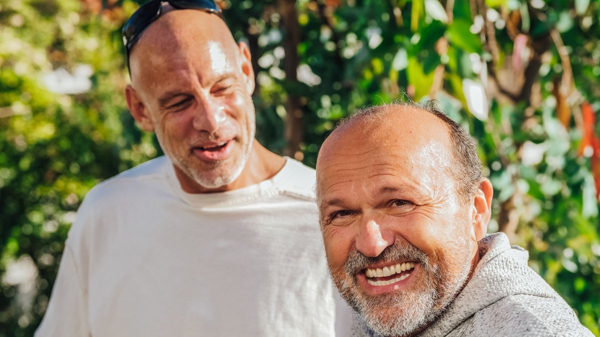 Two cheerful senior men enjoying a sunny day outdoors, embodying friendship and happiness.