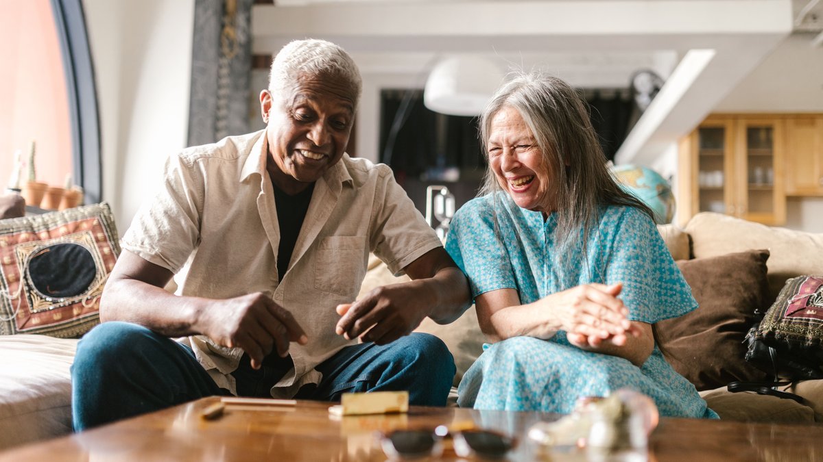 Happy senior couple laughing and enjoying time together at home on the sofa.