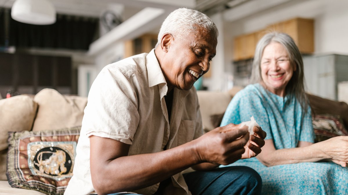 A joyful senior couple sharing a moment of laughter on the sofa in a cozy indoor setting.