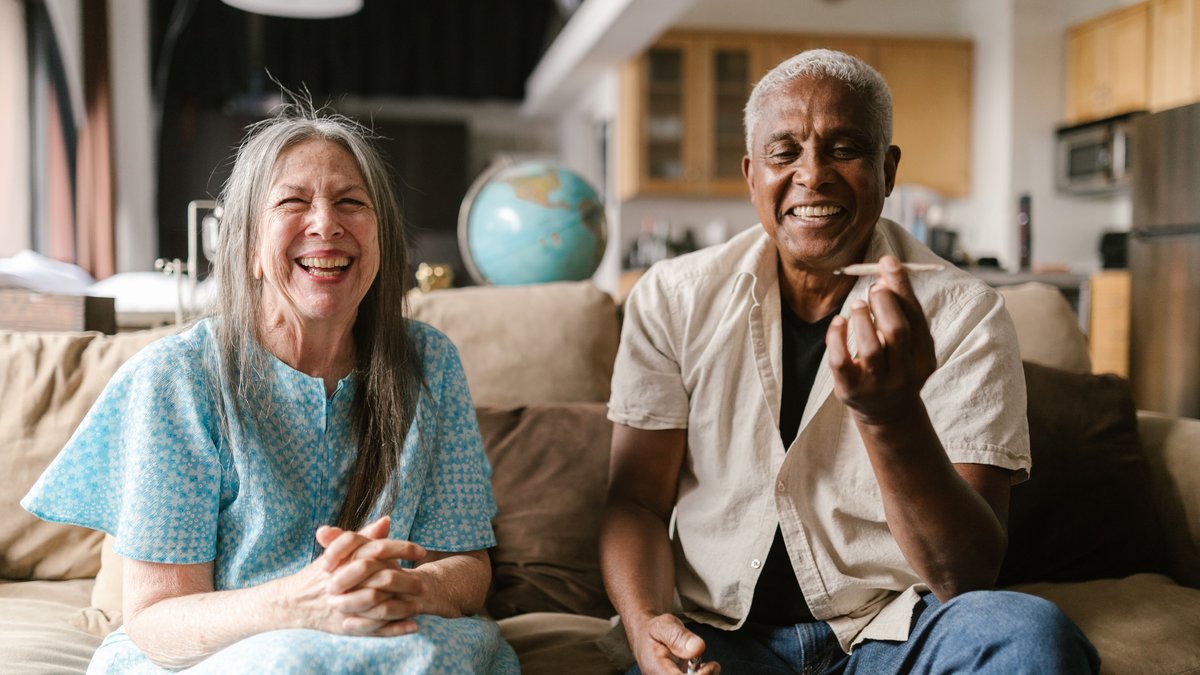 Elderly couple enjoying a relaxed afternoon indoors, smiling together.