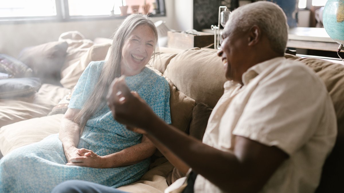Elderly couple enjoying a lighthearted moment at home, sharing smiles and laughter.