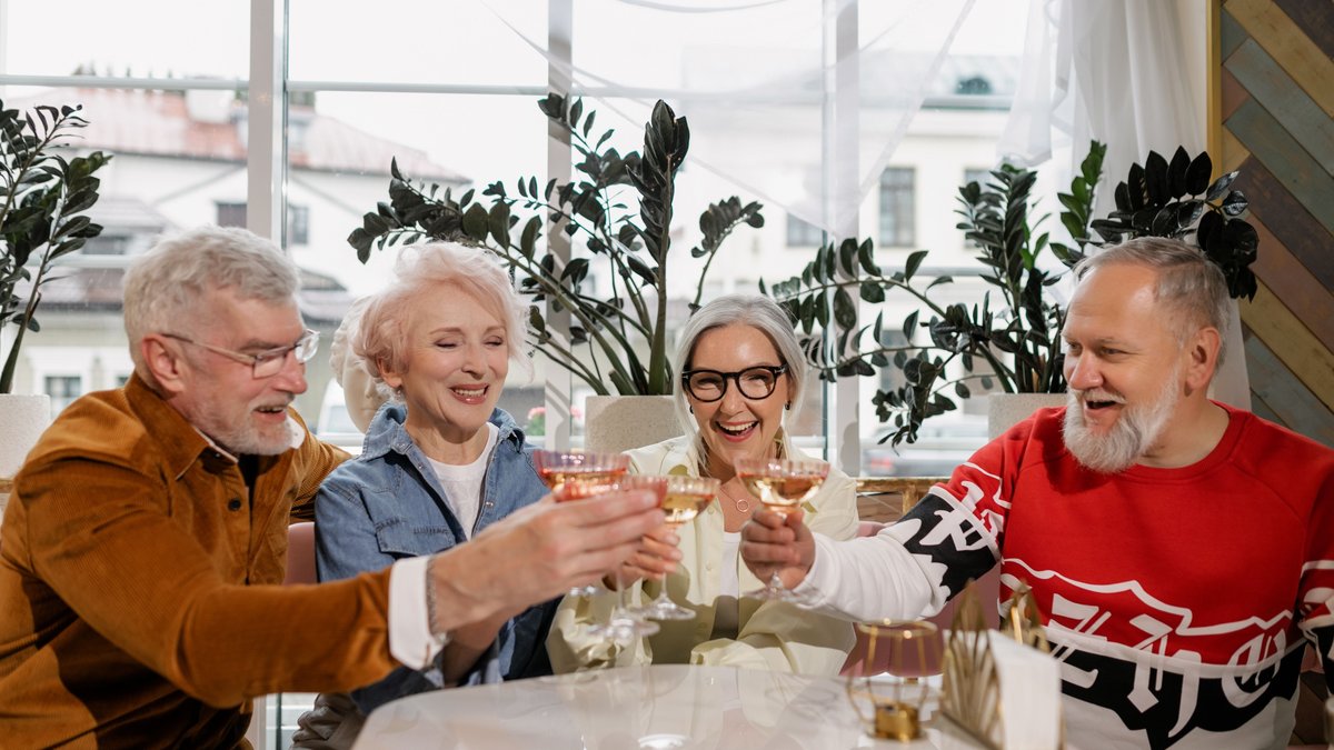 A cheerful group of senior adults enjoying a toast together indoors, celebrating friendship and happiness.