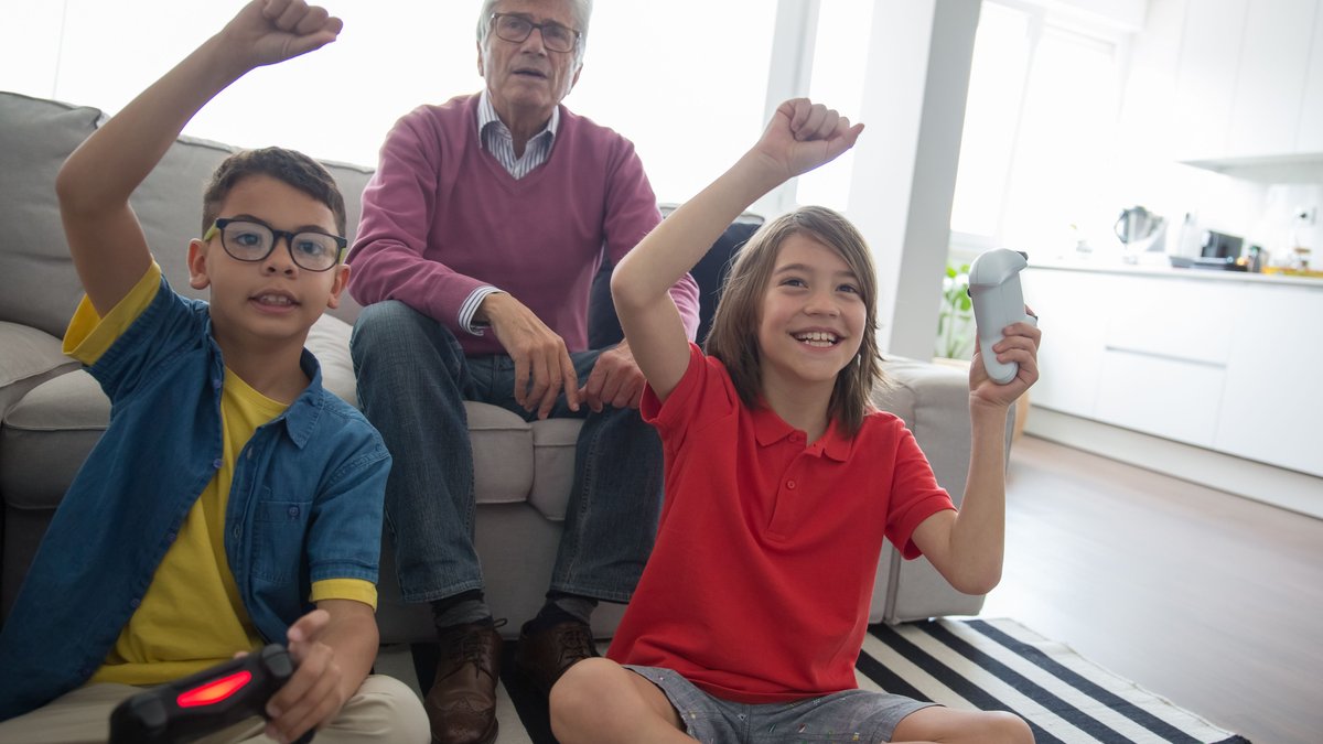 Happy family moment with grandfather and grandsons enjoying video games together on a cozy day indoors.