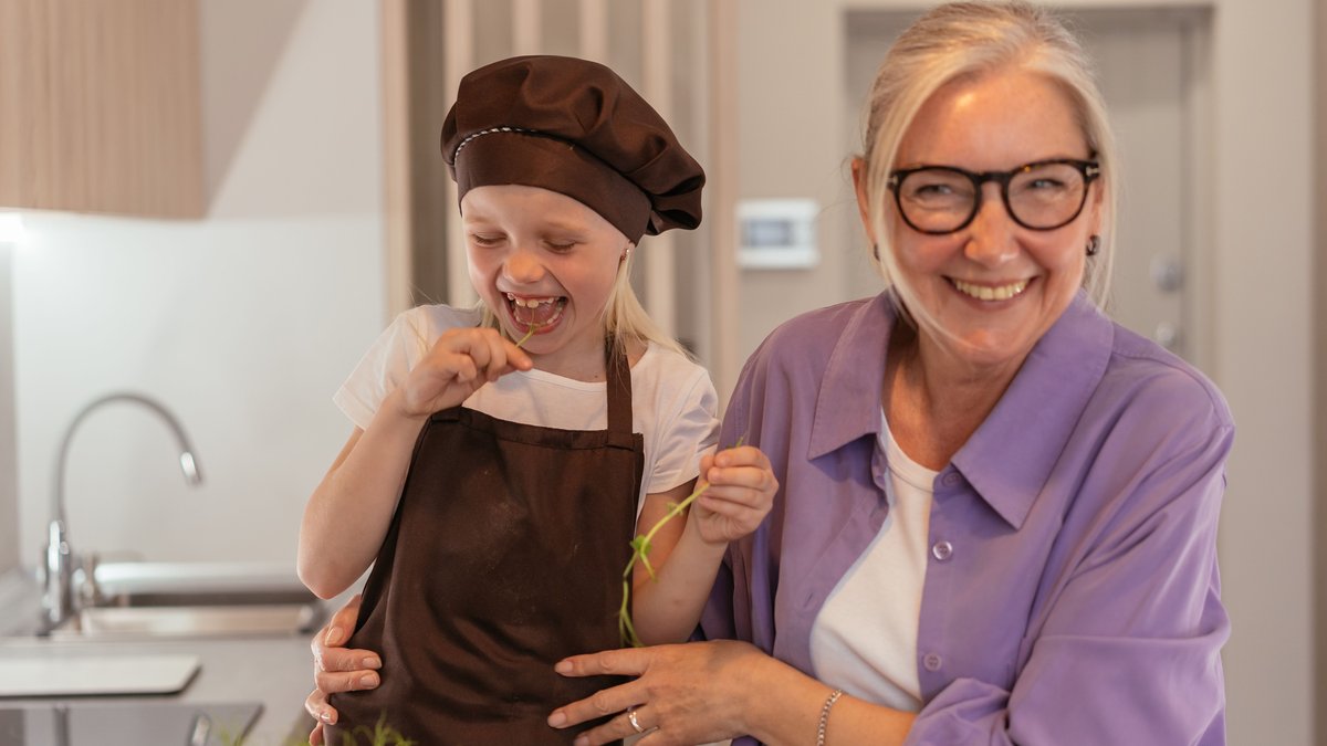 Happy grandmother and grandchild enjoying a fun cooking moment in the kitchen.