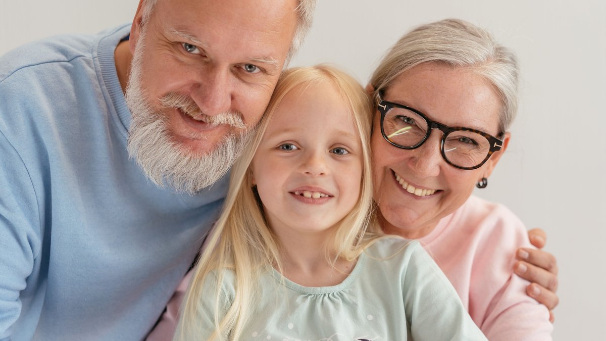 Happy grandparents and their grandchild smiling together indoors, showcasing family love and togetherness.