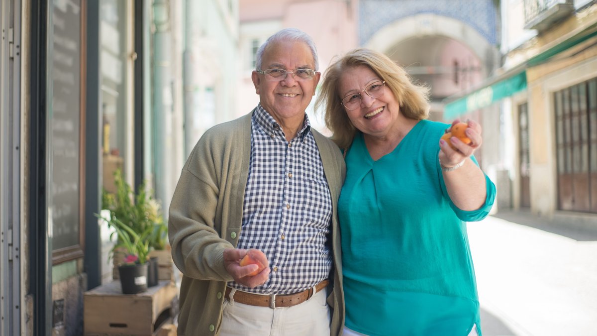 Smiling senior couple enjoying a day out shopping in a sunny Portuguese street.