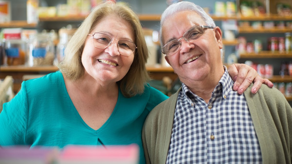 Happy senior couple smiling together inside a store in Portugal.