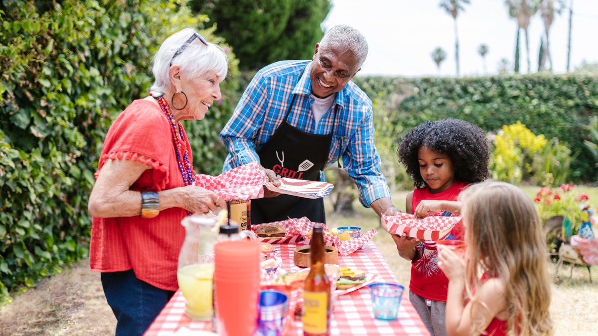 A joyful family gathers outdoors for a picnic, enjoying food and togetherness.