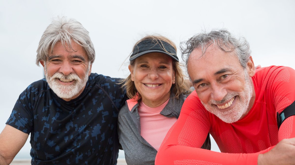 Senior friends in Portugal smiling and enjoying an outdoor fitness activity.